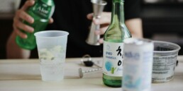 Green soju bottle and shot glass on a Korean dining table — Korea soju industry 2026