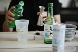 Green soju bottle and shot glass on a Korean dining table — Korea soju industry 2026
